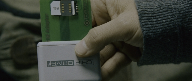 Wide shot frame from The Bourne Supremacy — sitting, hand, couch