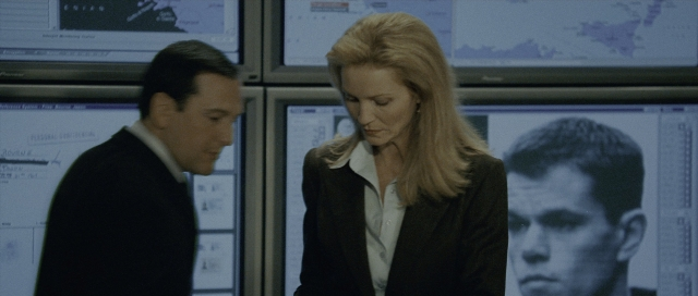 Wide shot frame from The Bourne Supremacy — standing, suit, tie