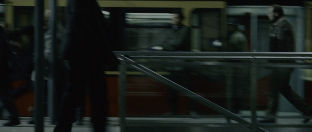 Wide shot frame from The Bourne Supremacy — sitting, walking, train
