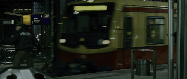 Wide shot frame from The Bourne Supremacy — walking, hat, night