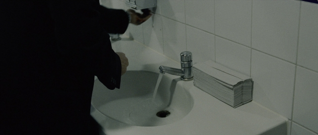 Wide shot frame from The Bourne Supremacy — standing, hand, bathroom