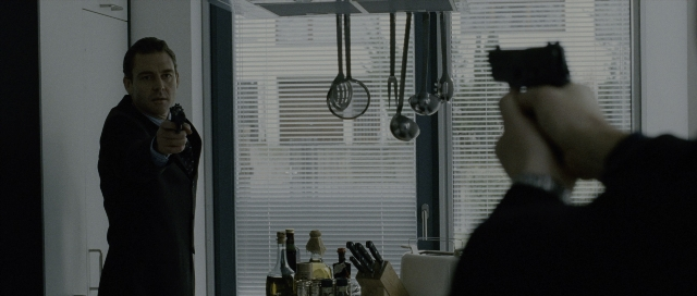 Wide shot frame from The Bourne Supremacy — standing, dialogue, kitchen