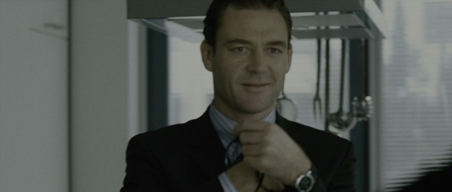 Medium shot frame from The Bourne Supremacy — standing, suit, tie