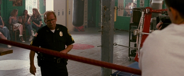 Wide shot frame from The Fighter — sitting, standing, room