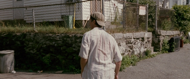 Wide shot frame from The Fighter — walking, street, hat
