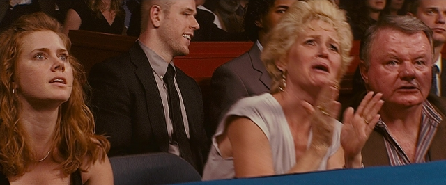 Wide shot frame from The Fighter — sitting, suit, dress