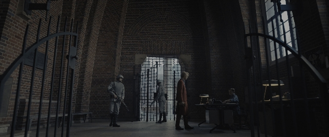Wide shot frame from The Hunger Games: The Ballad of Songbirds & Snakes — sitting, standing, room