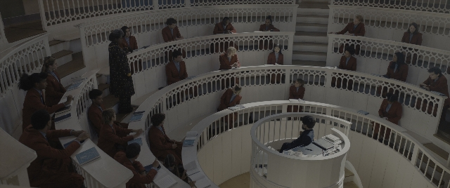 Wide shot frame from The Hunger Games: The Ballad of Songbirds & Snakes — sitting, standing, room