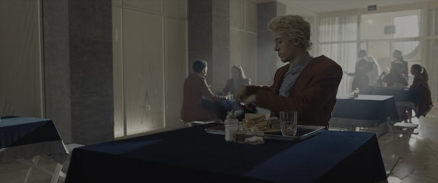 Wide shot frame from The Hunger Games: The Ballad of Songbirds & Snakes — sitting, standing, plate