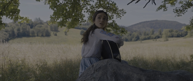 Wide shot frame from The Hunger Games: The Ballad of Songbirds & Snakes — sitting, dress, face