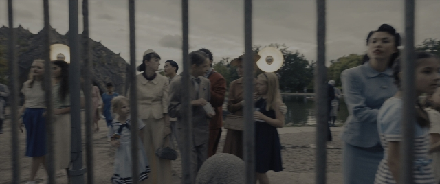 Wide shot frame from The Hunger Games: The Ballad of Songbirds & Snakes — standing, hat, suit