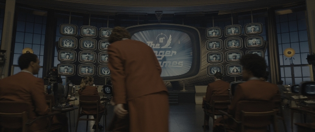 Wide shot frame from The Hunger Games: The Ballad of Songbirds & Snakes — sitting, standing, room