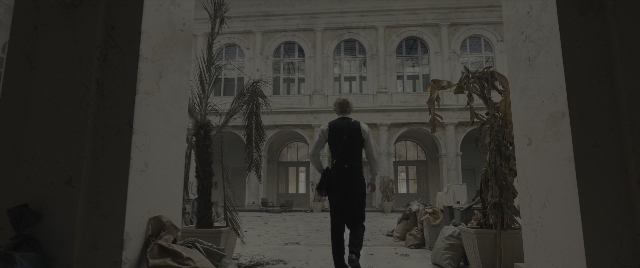 Wide shot frame from The Hunger Games: The Ballad of Songbirds & Snakes — walking, room, suit