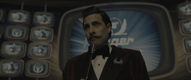 Medium shot frame from The Hunger Games: The Ballad of Songbirds & Snakes — standing, dialogue, suit