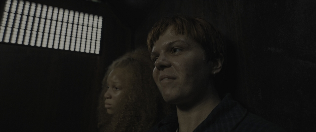Wide shot frame from The Hunger Games: The Ballad of Songbirds & Snakes — standing, room, face