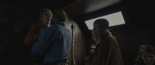 Wide shot frame from The Hunger Games: The Ballad of Songbirds & Snakes — standing, room, hat