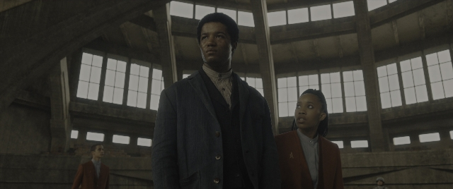 Wide shot frame from The Hunger Games: The Ballad of Songbirds & Snakes — standing, walking, suit