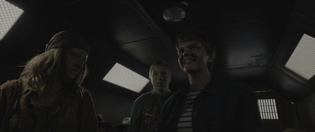 Wide shot frame from The Hunger Games: The Ballad of Songbirds & Snakes — standing, room, car