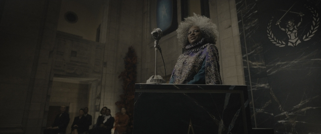 Wide shot frame from The Hunger Games: The Ballad of Songbirds & Snakes — sitting, standing, room