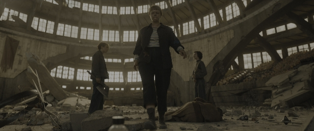 Wide shot frame from The Hunger Games: The Ballad of Songbirds & Snakes — standing, room, hand