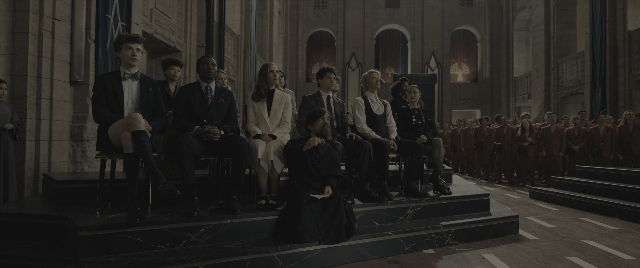 Wide shot frame from The Hunger Games: The Ballad of Songbirds & Snakes — sitting, standing, room