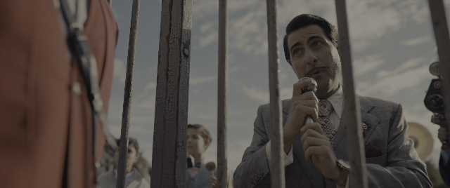 Wide shot frame from The Hunger Games: The Ballad of Songbirds & Snakes — standing, dialogue, hand