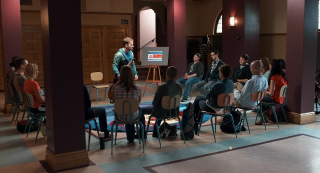 Medium shot frame from The Fault in Our Stars — sitting, book, standing