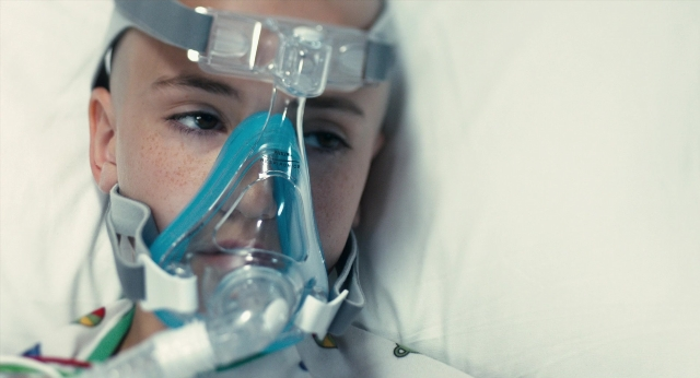 Wide shot frame from The Fault in Our Stars — room, bed, face