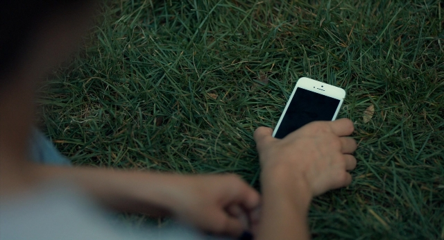 Wide shot frame from The Fault in Our Stars — bed, phone, person