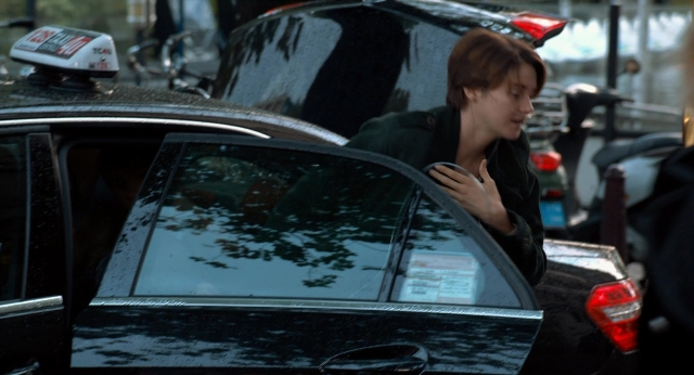 Wide shot frame from The Fault in Our Stars — standing, phone, street