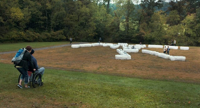 Wide shot frame from The Fault in Our Stars — walking, wheelchair, person
