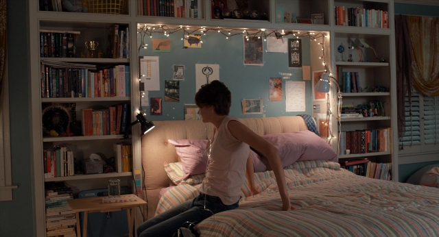 Wide shot frame from The Fault in Our Stars — sitting, book, room