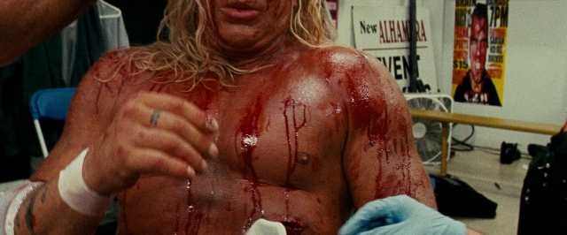 Wide shot frame from The Wrestler — room, hand, face