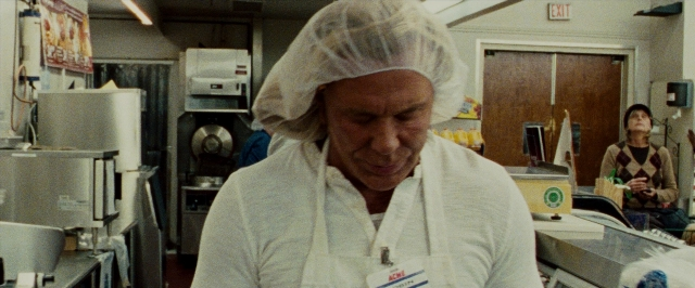 Wide shot frame from The Wrestler — sitting, standing, table