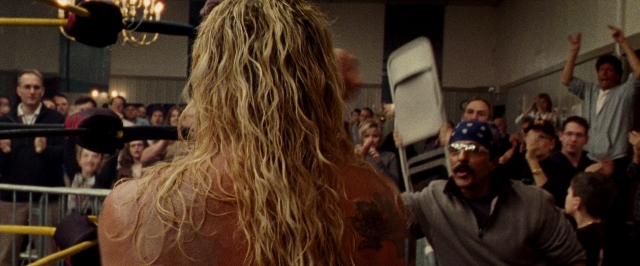 Wide shot frame from The Wrestler — standing, hat, hand
