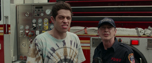 Wide shot frame from The King of Staten Island — standing, hat, uniform