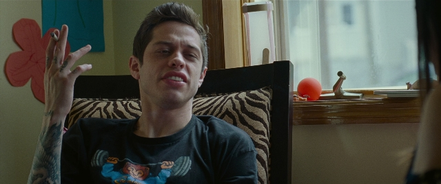 Medium shot frame from The King of Staten Island — sitting, room, hand
