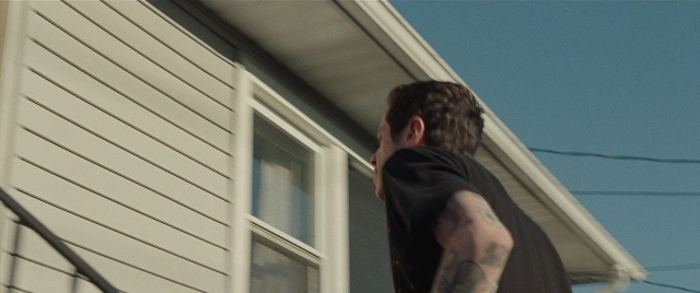 Wide shot frame from The King of Staten Island — standing, house, shirt