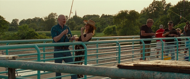 Wide shot frame from The King of Staten Island — standing, dialogue, hat