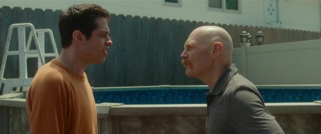 Wide shot frame from The King of Staten Island — standing, shirt, mustache