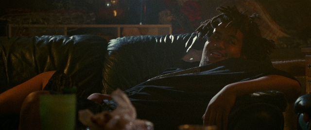 Wide shot frame from The King of Staten Island — room, shirt, couch