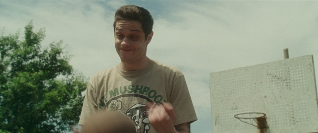 Wide shot frame from The King of Staten Island — standing, shirt, hair