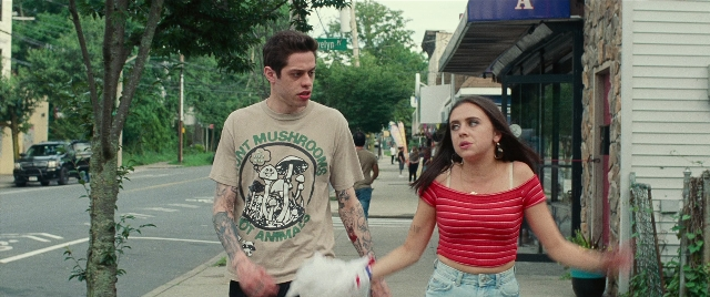 Wide shot frame from The King of Staten Island — walking, street, dog