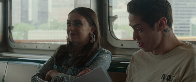 Wide shot frame from The King of Staten Island — sitting, shirt, face