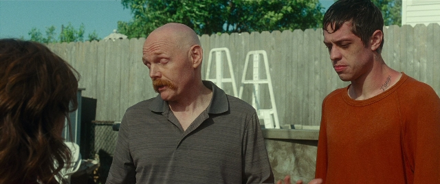 Wide shot frame from The King of Staten Island — standing, shirt, mustache
