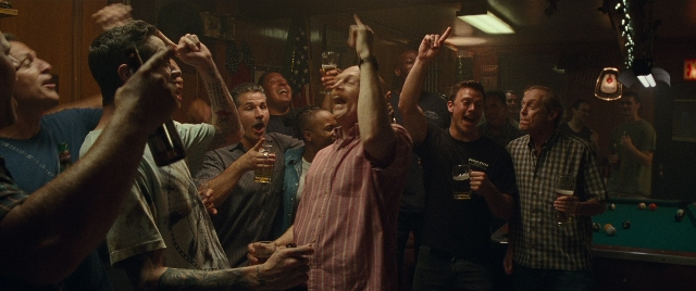 Wide shot frame from The King of Staten Island — standing, room, table