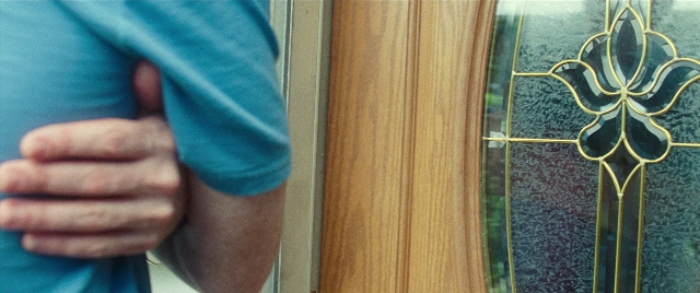 Wide shot frame from The King of Staten Island — door, hand, shirt