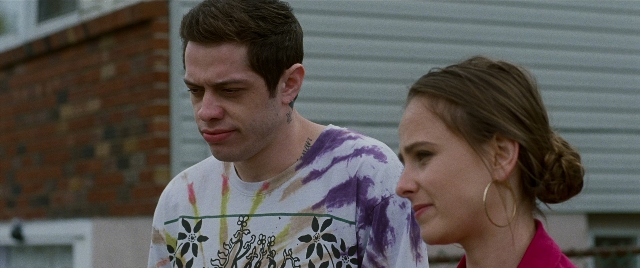 Wide shot frame from The King of Staten Island — standing, tie, shirt
