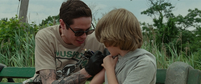Wide shot frame from The King of Staten Island — sitting, dialogue, hand
