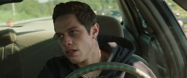 Wide shot frame from The King of Staten Island — sitting, street, car